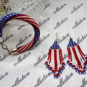 Peut inclure: Un ensemble de bijoux en perles aux couleurs rouge, blanc et bleu, rappelant le drapeau am&eacute;ricain. L'ensemble comprend un bracelet et une paire de boucles d'oreilles pendantes.