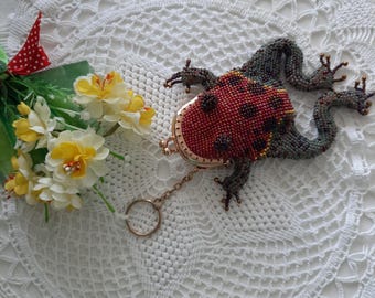 May include: A beaded frog purse with a red and black ladybug design. The purse has a gold chain and clasp.