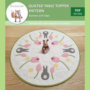 May include: A PDF pattern for a quilted table topper featuring bunnies and tulips. The pattern is an intermediate level and includes step-by-step instructions.