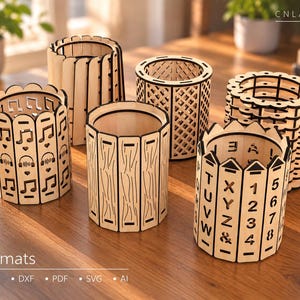 May include: Six cylindrical wooden pen holders with laser-cut designs including musical notes, headphones, hearts, a lattice pattern, wood grain textures, and alphanumeric characters. The text CNLASER is visible in the top right corner.