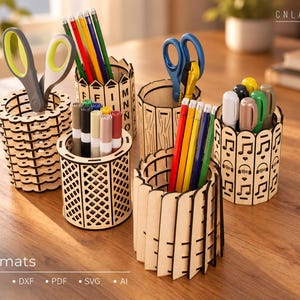 May include: Five cylindrical wooden pencil holders with laser-cut designs including letters, lattice patterns, vertical slats, and musical notes. The holders contain various colored pencils, markers, and scissors. Text includes CNLASER and Formats CDR, DXF, PDF, SVG, AI.