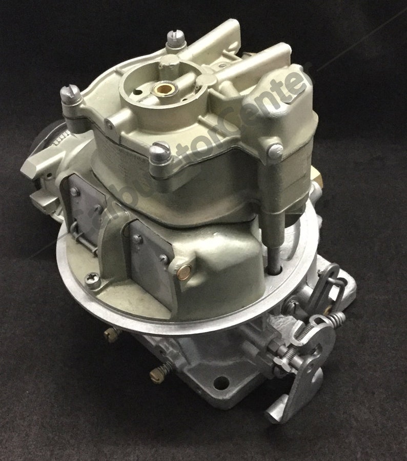 May include: A silver and brass carburetor with a lever and multiple screws. The carburetor is designed for a car engine.