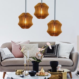 May include: A living room interior design featuring a grey sofa, three wooden pendant lights, a coffee table with a marble top, and a gold side table. The room is decorated with throw pillows, a vase with a protea flower, and a gold metal sculpture.