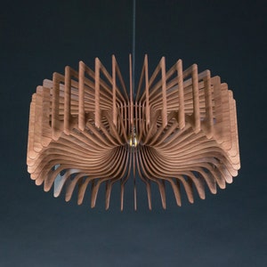 May include: A circular pendant light fitting constructed from numerous thin, curved wooden slats arranged in a radial pattern. The light features a central brass-coloured socket and is suspended by a single thin cord, creating a layered, fan-like structure.