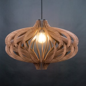 Op de afbeelding: Een hanglamp met een bolvormige, open kap opgebouwd uit gebogen, lichtbruine houten latten. De structuur omringt een enkele, gloeiende lamp die aan een dun zwart snoer vanuit het midden naar beneden hangt.