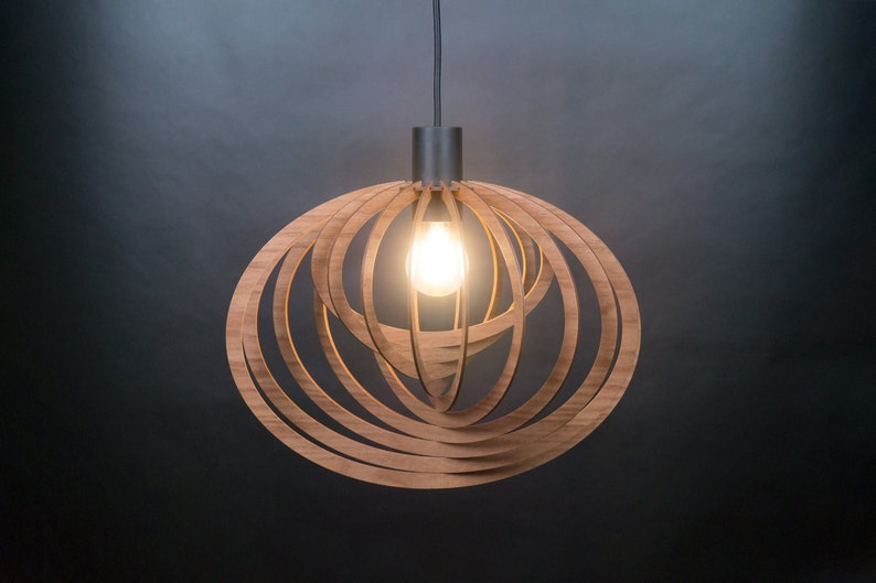 Puede incluir: Una l&aacute;mpara colgante de madera con un dise&ntilde;o circular y en capas. La l&aacute;mpara est&aacute; hecha de finas tiras de madera de color marr&oacute;n claro que est&aacute;n dispuestas en espiral. Se puede ver una bombilla dentro de la l&aacute;mpara.