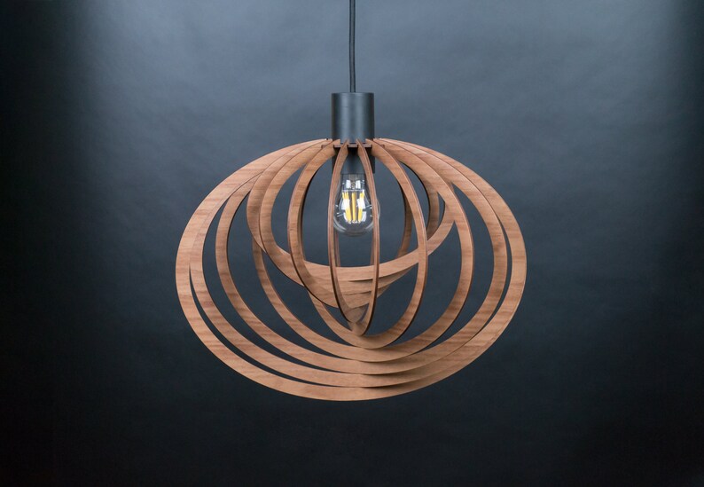 Puede incluir: Una l&aacute;mpara colgante de madera moderna con un dise&ntilde;o circular. La l&aacute;mpara est&aacute; hecha de m&uacute;ltiples capas de madera que se apilan y curvan para crear una forma esf&eacute;rica. La l&aacute;mpara tiene un cable negro y una base de metal negro.
