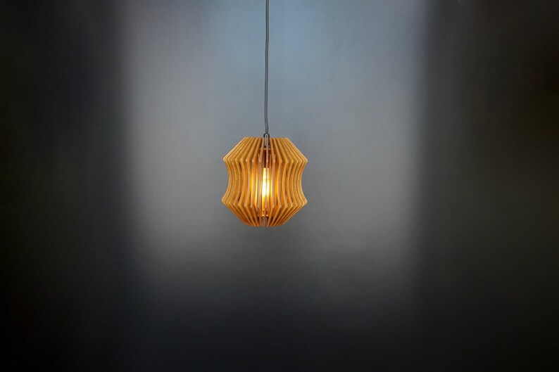 May include: A wooden pendant light with a geometric design. The light is hanging from a ceiling and is turned on, illuminating the room.