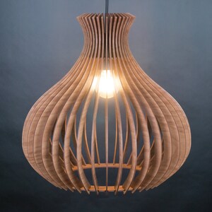 May include: A wooden pendant light fixture with a bulb inside. The light has a unique design, with vertical wooden slats forming a bulbous shape. The light is suspended from a black cord against a dark background.
