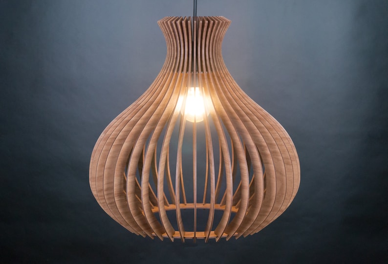 May include: A wooden pendant light fixture with a bulb inside. The light has a unique design, with vertical wooden slats forming a bulbous shape. The light is suspended from a black cord against a dark background.