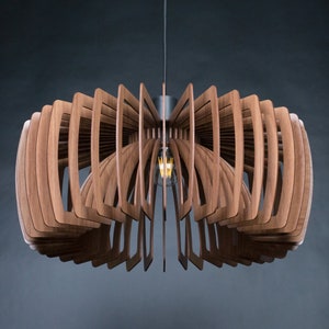May include: A wooden pendant light fixture with a geometric design. The light fixture is made of multiple thin pieces of wood that are arranged in a circular pattern. The light fixture is suspended from the ceiling by a single cord.