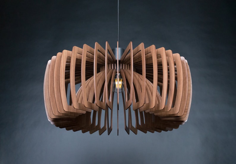 May include: A wooden pendant light fixture with a geometric design. The light fixture is made of multiple thin pieces of wood that are arranged in a circular pattern. The light fixture is suspended from the ceiling by a single cord.