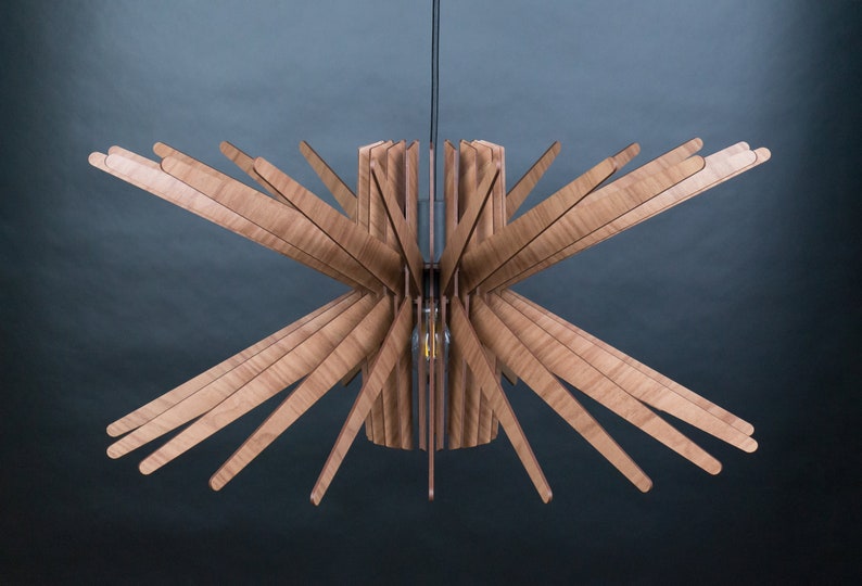 K&ouml;nnte beinhalten: Eine Deckenleuchte aus Holz mit einem Sternburst-Design. Die Leuchte besteht aus mehreren d&uuml;nnen Holzlamellen, die von einem zentralen Zylinder nach au&szlig;en strahlen.
