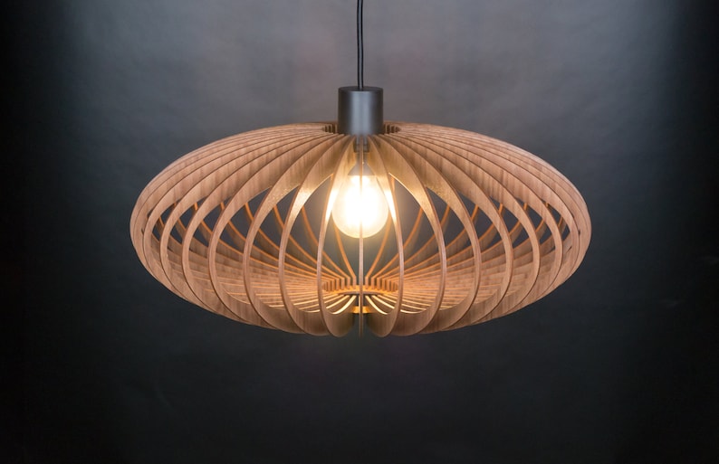 May include: A wooden pendant light fixture with a circular, open-weave design. The light fixture is suspended from a black cord and has a black metal canopy.
