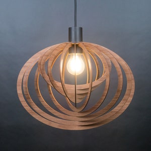 Puede incluir: Una l&aacute;mpara colgante moderna de madera con un dise&ntilde;o circular. La l&aacute;mpara tiene un acabado de madera natural c&aacute;lido y una sola bombilla.