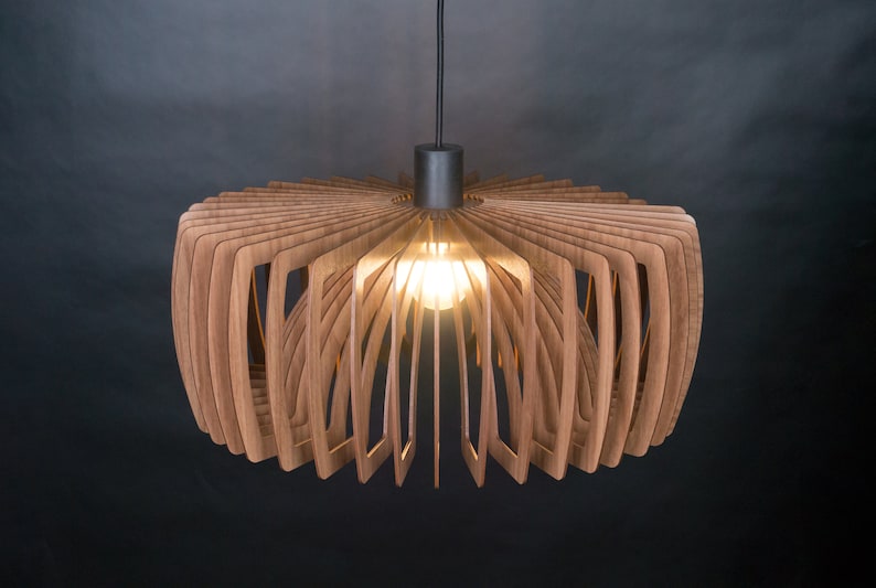 May include: A modern, wooden pendant light fixture with a circular, fan-shaped design. The light is made of thin, layered wood strips that create a unique and intricate pattern. The light is illuminated by a single light bulb.