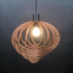 Puede incluir: Una l&aacute;mpara colgante de madera con un dise&ntilde;o circular y geom&eacute;trico. La luz est&aacute; hecha de finas tiras de madera que se entrelazan para crear una forma esf&eacute;rica. La luz est&aacute; iluminada por una sola bombilla.