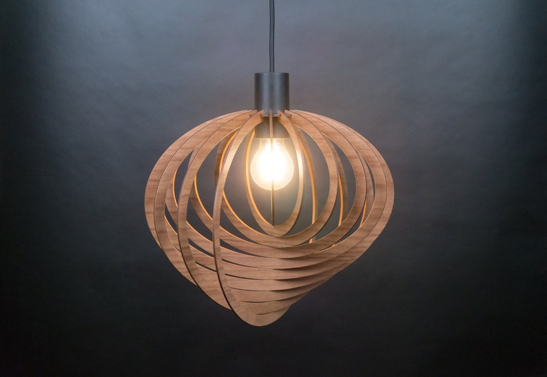 Puede incluir: Una l&aacute;mpara colgante de madera con un dise&ntilde;o circular y geom&eacute;trico. La luz est&aacute; hecha de finas tiras de madera que se entrelazan para crear una forma esf&eacute;rica. La luz est&aacute; iluminada por una sola bombilla.