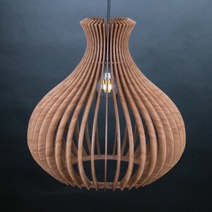 May include: A wooden pendant light fixture with a unique, open design. The light is made of curved wooden slats, creating a layered, organic shape. An Edison-style light bulb hangs in the center, casting a warm glow. The fixture is suspended from a black cord.