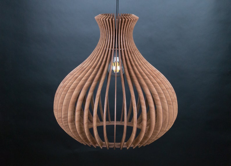 May include: A wooden pendant light fixture with a unique, open design. The light is made of curved wooden slats, creating a layered, organic shape. An Edison-style light bulb hangs in the center, casting a warm glow. The fixture is suspended from a black cord.