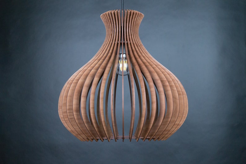 May include: A wooden pendant light fixture with a bulb. The light has a unique design, with vertical wooden slats forming a bulbous shape. The light fixture is suspended from a black cord against a dark gray background. The light bulb is visible inside the fixture.