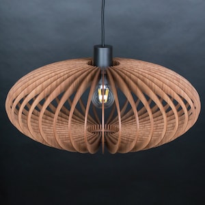 May include: A wooden pendant light fixture with a geometric design. The light fixture is made of thin strips of wood that are arranged in a circular pattern. The light fixture is hanging from a black cord.