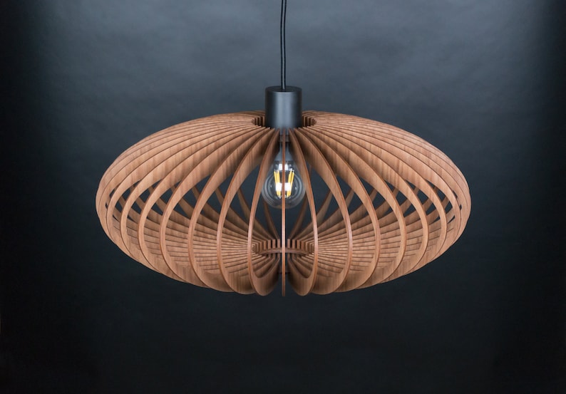 May include: A wooden pendant light fixture with a geometric design. The light fixture is made of thin strips of wood that are arranged in a circular pattern. The light fixture is hanging from a black cord.