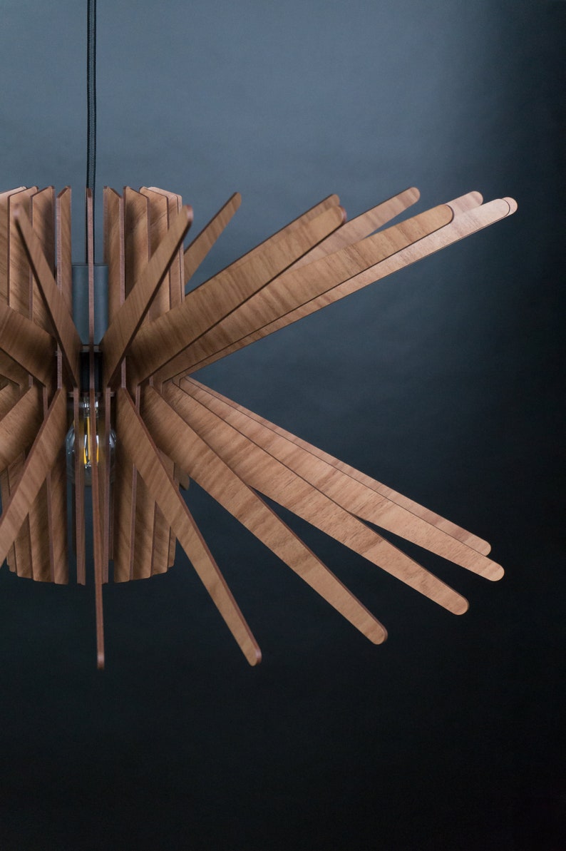 K&ouml;nnte beinhalten: Eine Deckenleuchte aus Holz mit einem runden Sockel und mehreren Holzlamellen, die sich nach au&szlig;en erstrecken und ein Sternenmuster bilden.