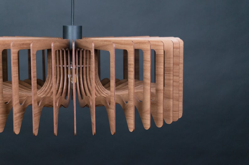 May include: A modern wooden pendant light fixture with a circular design. The light is made of multiple thin, curved wooden slats that create a geometric pattern. The fixture has a black cord and a black metal canopy.
