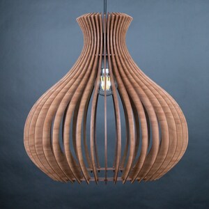 May include: A wooden pendant light fixture with a bulb. The light has a unique design, with vertical wooden slats forming a bulbous shape. The light fixture is suspended from the ceiling by a black cord. The wood has a warm, natural tone.
