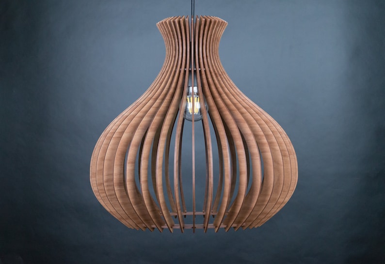 May include: A wooden pendant light fixture with a bulb. The light has a unique design, with vertical wooden slats forming a bulbous shape. The light fixture is suspended from the ceiling by a black cord. The wood has a warm, natural tone.
