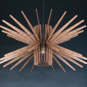 May include: A wooden ceiling light fixture with a starburst design. The light fixture is made of thin, wooden slats that radiate outwards from a central point. The light fixture is suspended from the ceiling by a thin wire.