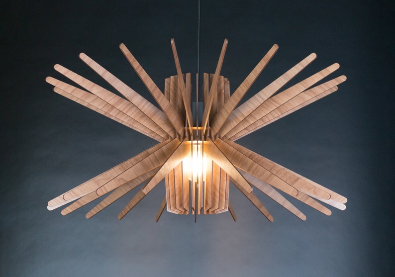 May include: A wooden pendant light fixture with a cylindrical shade and multiple wooden slats extending outward, creating a starburst effect. The light is on and illuminating the room.