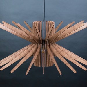 May include: A wooden ceiling light fixture with a starburst design. The light fixture is made of multiple thin wooden slats that radiate outwards from a central cylinder.
