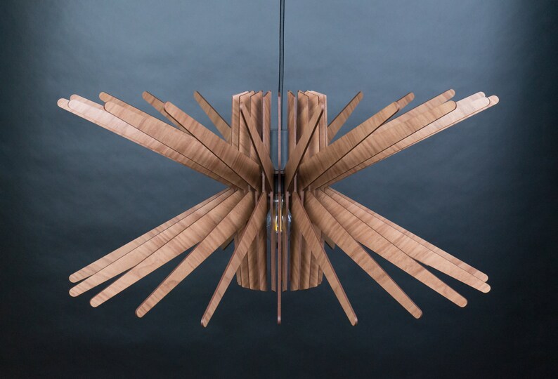 May include: A wooden ceiling light fixture with a starburst design. The light fixture is made of multiple thin wooden slats that radiate outwards from a central cylinder.