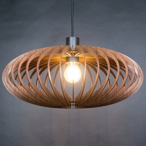 May include: A modern wooden pendant light with a geometric design. The light fixture is made of thin strips of wood that are arranged in a circular pattern. The light is suspended from a black cord and has a single light bulb.