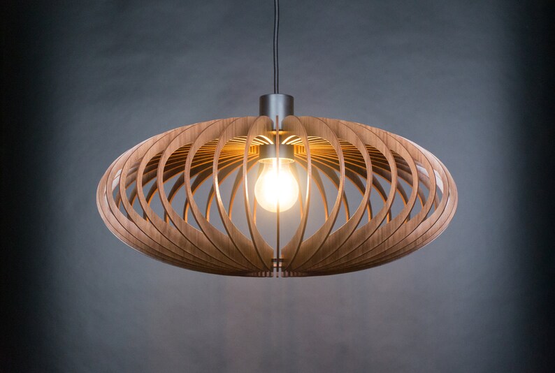 May include: A modern wooden pendant light with a geometric design. The light fixture is made of thin strips of wood that are arranged in a circular pattern. The light is suspended from a black cord and has a single light bulb.