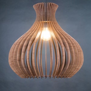 May include: A wooden pendant light fixture with a bulb illuminated inside. The light is made of curved wooden slats, creating a layered, open design. The fixture hangs from a single cord against a dark gray background.