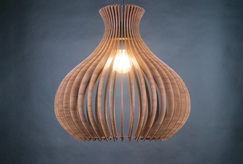 May include: A wooden pendant light fixture with a bulb illuminated inside. The light is made of curved wooden slats, creating a layered, open design. The fixture hangs from a single cord against a dark gray background.