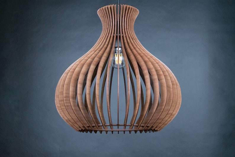 May include: A wooden pendant light fixture with a bulb visible inside. The light has a unique design, with vertical wooden slats forming a bulbous shape. The fixture is suspended from a wire against a dark gray background.