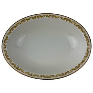Może przedstawiać: Owalny biały półmisek z złotą obwódką i dekoracyjnym obramowaniem z zielonych i złotych elementów kwiatowych. Naczynie ma błyszczące wykończenie i nadaje się do serwowania potraw.