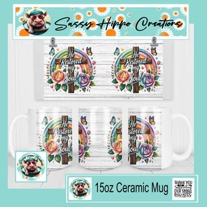 May include: A white 15oz ceramic mug featuring a graphic print of a wooden cross, a colorful rainbow, roses, and butterflies. The text "He Restored my Soul" is printed on the mug. The design includes a light wood grain background pattern.