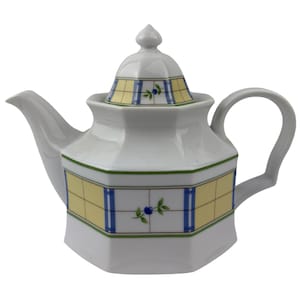 May include: White ceramic teapot with a lid, spout, and handle. The teapot features yellow and blue geometric patterns with green and blue floral accents. The design is repeated on the lid and body of the teapot.