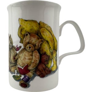 Könnte beinhalten: Ein weißer Keramikbecher mit einer farbigen Illustration von mehreren Teddybären. Ein Bär ist gelb, ein anderer ist hellbraun und liest in einem kleinen roten Buch, und ein kleinerer Bär ist dunkelbraun. Der Becher hat einen geschwungenen Henkel.