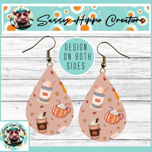 May include: Teardrop-shaped earrings featuring a light pink background with a repeating pattern of pumpkins, whipped cream-topped coffee cups, and autumn leaves. The earrings have gold-toned metal hooks and a design printed on both sides.