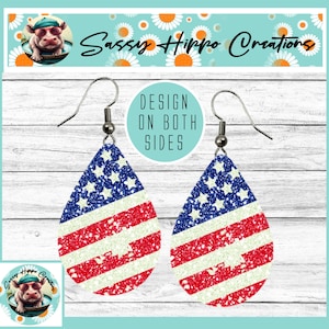 May include: A pair of teardrop-shaped earrings featuring a glittery American flag pattern with blue stars and red and white stripes. The earrings have silver-toned metal fishhook wires and a circular text overlay that reads DESIGN ON BOTH SIDES.