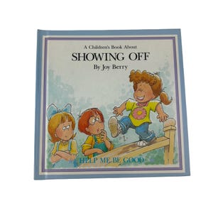 May include: A children's book titled A Children's Book About SHOWING OFF by Joy Berry, part of the Help Me Be Good series. The cover features a colorful illustration of three children, with one child balancing on a wooden fence while two others watch.