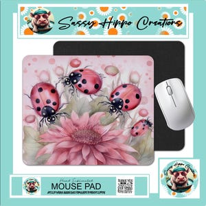 May include: A rectangular mouse pad featuring a pink floral design with four red ladybugs with black spots. The mouse pad has a black rubber base and is displayed with a white computer mouse. The text Sassy Hippo Creations is visible.