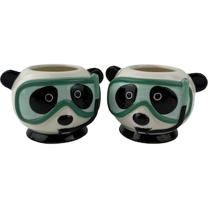 Puede incluir: Dos macetas de cerámica con forma de panda. Cada maceta tiene una base blanca con rasgos de panda negros, incluyendo ojos, orejas y nariz. Llevan máscaras de buceo verdes. Las macetas tienen una abertura redonda en la parte superior.