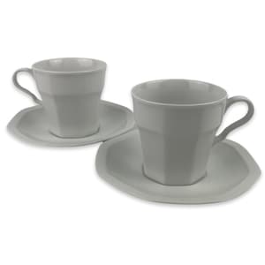 May include: Two matching white teacups and saucers. The cups have a faceted design and curved handles. The saucers are a unique, irregular shape. The set is made of ceramic and is suitable for serving tea or coffee.